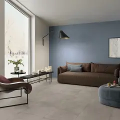 Soggiorno moderno con **pavimento grigio** e **pareti tortora** che creano un'atmosfera rilassante. Divano marrone, poltrona di design e opere d'arte completano l'arredo.