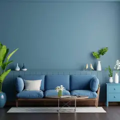 Soggiorno con divano blu e pareti color carta da zucchero. Piante verdi e decorazioni creano un'atmosfera rilassante.