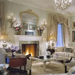 Salotto elegante con camino acceso, fiori color cremisi e un lampadario scintillante.