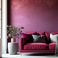 Divano fucsia acceso con cuscini in varie tonalità di rosa e grigio, su sfondo murale viva magenta.