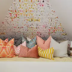 Un letto accogliente con tanti cuscini decorativi dai motivi vivaci e colorati, pronti per un riposo da sogno.