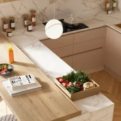 Top cucina con materiali innovativi: piano in legno chiaro, marmo bianco e oro, mobili color pesca. Frutta fresca, verdure e libri sul bancone.