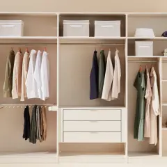 Un armadio bianco ben organizzato con vestiti appesi, scatole contenitive e cassetti.