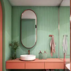 Bagno moderno con lavabo bianco, mobile color pesca e pareti verdi a coste. Idee bagni piccoli bellissimi con specchio ovale e dettagli in rame.