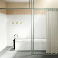 Bagno moderno con vasca e rubinetto a colonna. Una tenda color crema offre un'alternativa alla tenda doccia, separando la zona.