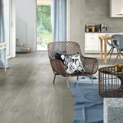 Soggiorno e cucina moderni con pavimento grigio chiaro, mobili di design e un'ampia vetrata sul giardino.