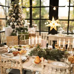 Tavola imbandita per Natale con torta, arrosti e candele. Un albero addobbato e regali creano l'atmosfera perfetta per le idee decorare la cucina per natale.