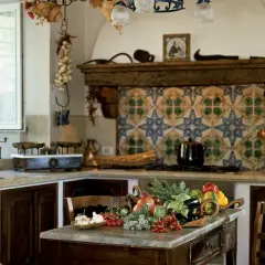 Cucine montagna piccole con un ricco tavolo di verdure fresche. Pareti decorate con maioliche colorate e dettagli rustici.