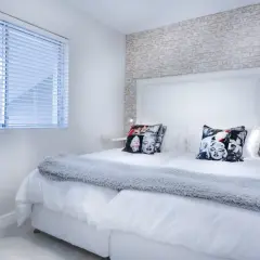 Camera da letto moderna con cuscini di Marilyn Monroe. I colori neutri e la luce soffusa creano un'atmosfera rilassante, perfetta per la cromoterapia.