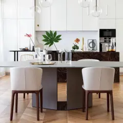 Un elegante tavolo da pranzo con sedie imbottite, parte di un progetto di casa in stile contemporaneo. La cucina moderna è visibile sullo sfondo.