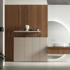 Un elegante bagno minimal con mobile sospeso in legno, lavabo bianco e specchio circolare retroilluminato.