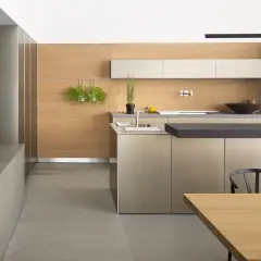 Cucina moderna con ante color tortora e pareti in legno chiaro. Un'isola centrale con piano scuro e un tavolo in legno completano l'ambiente.