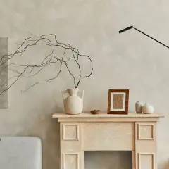 Un camino decorato con vasi, un quadro e rami secchi, perfetto per decorare una parete spoglia.