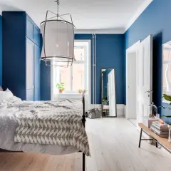Accogliente camera da letto blu con letto matrimoniale, armadio blu e specchio a figura intera.