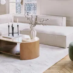 Tavolino con finitura in legno betulla colore, accanto a un divano bianco e una poltrona verde.