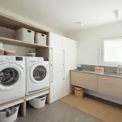 Progetto bagno con lavanderia: lavatrice, asciugatrice, lavabo e armadi, tutto organizzato per un ambiente funzionale.