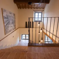 Scale interne con mattoni a vista e un'elegante ringhiera in ferro battuto. Le idee illuminazione scale interne sono valorizzate da lampadine a vista che creano un'atmosfera calda e accogliente.