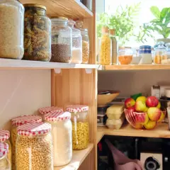 Dispensa organizzata con barattoli di pasta, riso, legumi e frutta fresca. Tutto in ordine per cucinare.