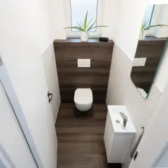 Bagno con wc e lavandino compatti, dimostra le dimensioni minime bagno solo wc. Specchio e pianta decorano lo spazio.