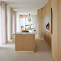 Ingresso con boiserie moderne in legno, isola cucina e tende colorate.