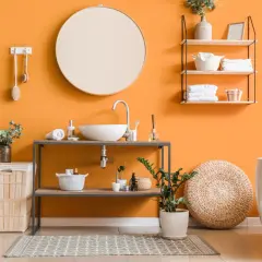 Bagno moderno con pareti arancioni vivaci, lavabo sospeso, vasca bianca e idee pittura bagno che ispirano freschezza e stile.