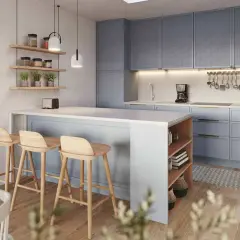 Accogliente piccola cucina con isola a muro, sgabelli in legno e pensili azzurri.