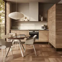 Ecco come arredare una cucina moderna: mobili in legno, tavolo rotondo con sedie bianche e grande finestra con vista sul verde.