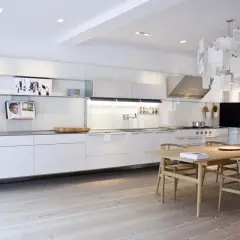 Cucina moderna e minimalista, con mobili bianchi lineari e un tavolo in legno. Un esempio di come progettare una cucina funzionale ed elegante.