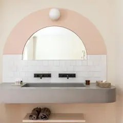 Lavabo bagno in muratura moderno con doppio rubinetto nero e specchio ad arco. Idee per un bagno di design.