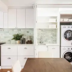 Soluzione elegante per come nascondere lavatrice e asciugatrice in una cucina moderna, integrate in una nicchia con ante a scomparsa.