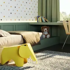 Arredamento camera neonato: letto accogliente, sgabello a forma di elefante giallo, orsacchiotto e scrivania con vista sul verde.