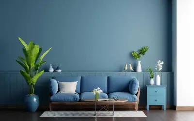 Soggiorno con divano blu e pareti color carta da zucchero. Piante verdi e decorazioni creano un'atmosfera rilassante.