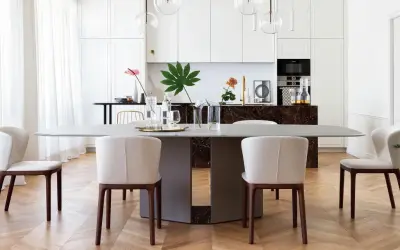Un elegante tavolo da pranzo con sedie imbottite, parte di un progetto di casa in stile contemporaneo. La cucina moderna è visibile sullo sfondo.