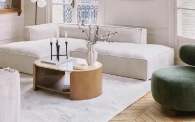 Tavolino con finitura in legno betulla colore, accanto a un divano bianco e una poltrona verde.