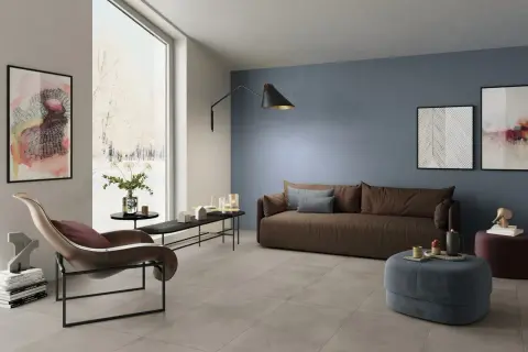 Soggiorno moderno con **pavimento grigio** e **pareti tortora** che creano un'atmosfera rilassante. Divano marrone, poltrona di design e opere d'arte completano l'arredo.
