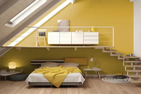 Camera da letto moderna con pareti in varie tonalità di giallo, un letto con coperta gialla e una scala a vista.