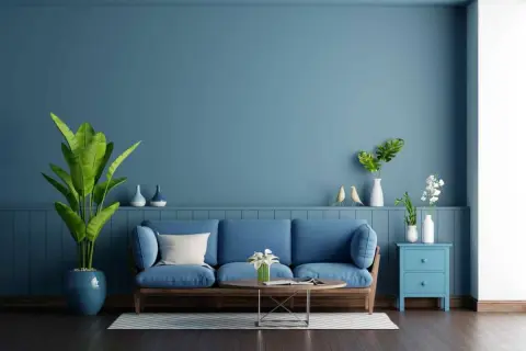 Soggiorno con divano blu e pareti color carta da zucchero. Piante verdi e decorazioni creano un'atmosfera rilassante.