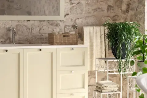 Bagni stile rustico con mobile lavabo color crema, pareti in pietra grezza e piante verdi.
