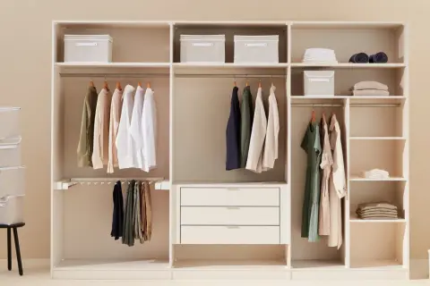 Un armadio bianco ben organizzato con vestiti appesi, scatole contenitive e cassetti.