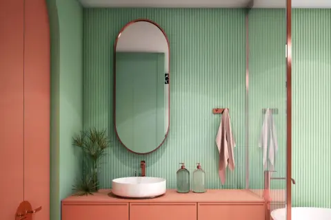 Bagno moderno con lavabo bianco, mobile color pesca e pareti verdi a coste. Idee bagni piccoli bellissimi con specchio ovale e dettagli in rame.