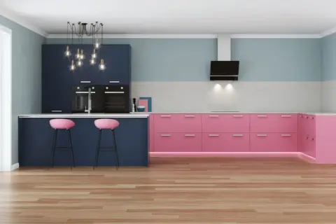 Moderna cucina con pensili blu scuro e basi rosa acceso. Due sgabelli rosa completano l'isola.
