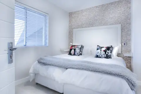Camera da letto moderna con cuscini di Marilyn Monroe. I colori neutri e la luce soffusa creano un'atmosfera rilassante, perfetta per la cromoterapia.