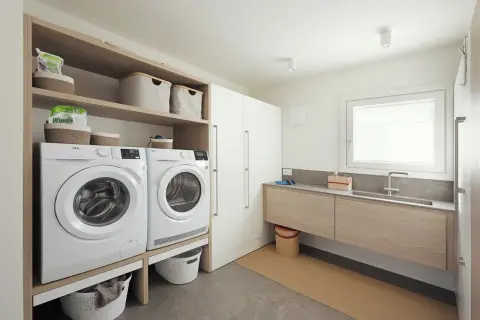 Progetto bagno con lavanderia: lavatrice, asciugatrice, lavabo e armadi, tutto organizzato per un ambiente funzionale.