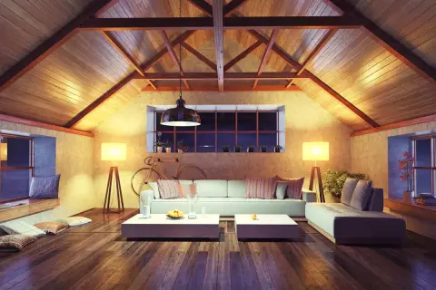 Accogliente soggiorno mansardato con travi a vista e illuminazione calda. Ottime idee sottotetto molto basso per creare un ambiente confortevole.