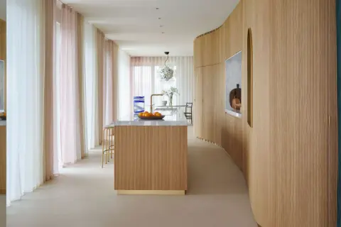 Ingresso con boiserie moderne in legno, isola cucina e tende colorate.