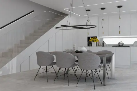Un tavolo con sedie grigie in una moderna cucina bianca, con scala a vista e illuminazione minimalista. Perfette idee cucina bianca per un ambiente luminoso.
