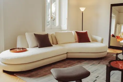 Soggiorno accogliente con divano bianco, cuscini colorati e vassoio. Un esempio di come fare decluttering per un ambiente sereno.