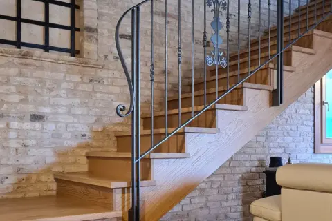 Scale interne in legno con ringhiera in ferro battuto, un'idea di design che unisce rustico e moderno.
