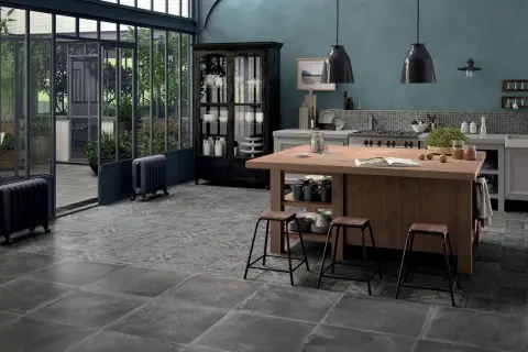 Cucina con isola in legno, sgabelli, vetrata e pavimenti con idee piastrelle cucina effetto pietra e decoro vintage.