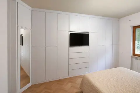 Armadio a muro bianco con TV integrata e specchio, perfetto per idee armadio camera da letto piccola.